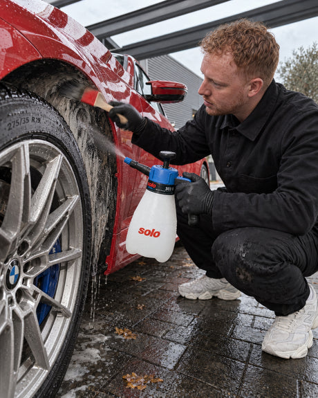 solo CLEANLine 303 B spryskuje środkiem nadkole, pędzelek Koch-Chemie czyści krawędź nadkola w BMW M2