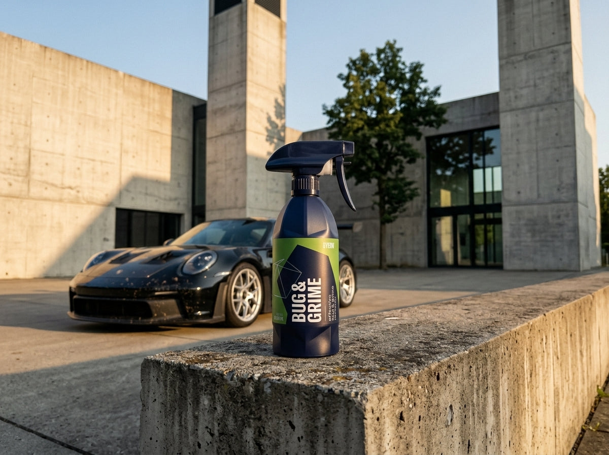 GYEON Q2M Bug Grime 500ml Flasche auf Sichtbeton vor einem Porsche – Hero Shot