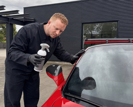 Jasper untersucht den Ölfilm auf der Frontscheibe eines roten Porsche 911 GT3 RS vor der Detailing1-Halle — gezeigt im Artikel „Ölfilm auf der Scheibe lösen in zwei Schritten“