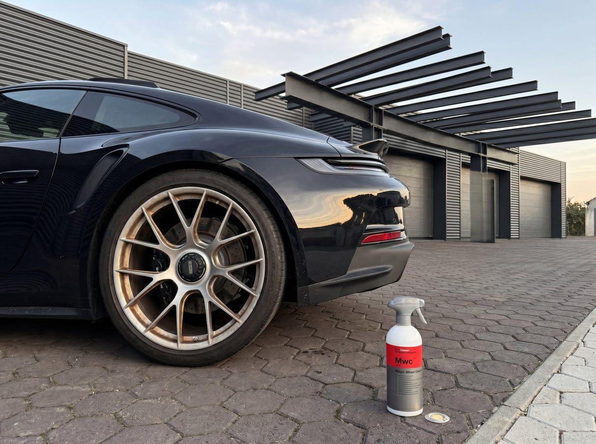 Koch-Chemie Magic Wheel Cleaner MWC 500ml auf Pflastersteinen neben verschmutzter Porsche-Felge — Werkstatt-Szene