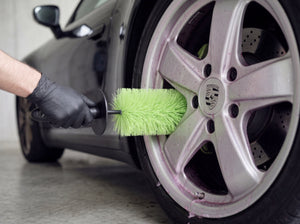 Felgenbürste wird mit Nitrilhandschuh zwischen Speichen einer Porsche Fuchsfelge geführt während pink-violetter Alu-Teufel Gel-Reaktion sichtbar ist