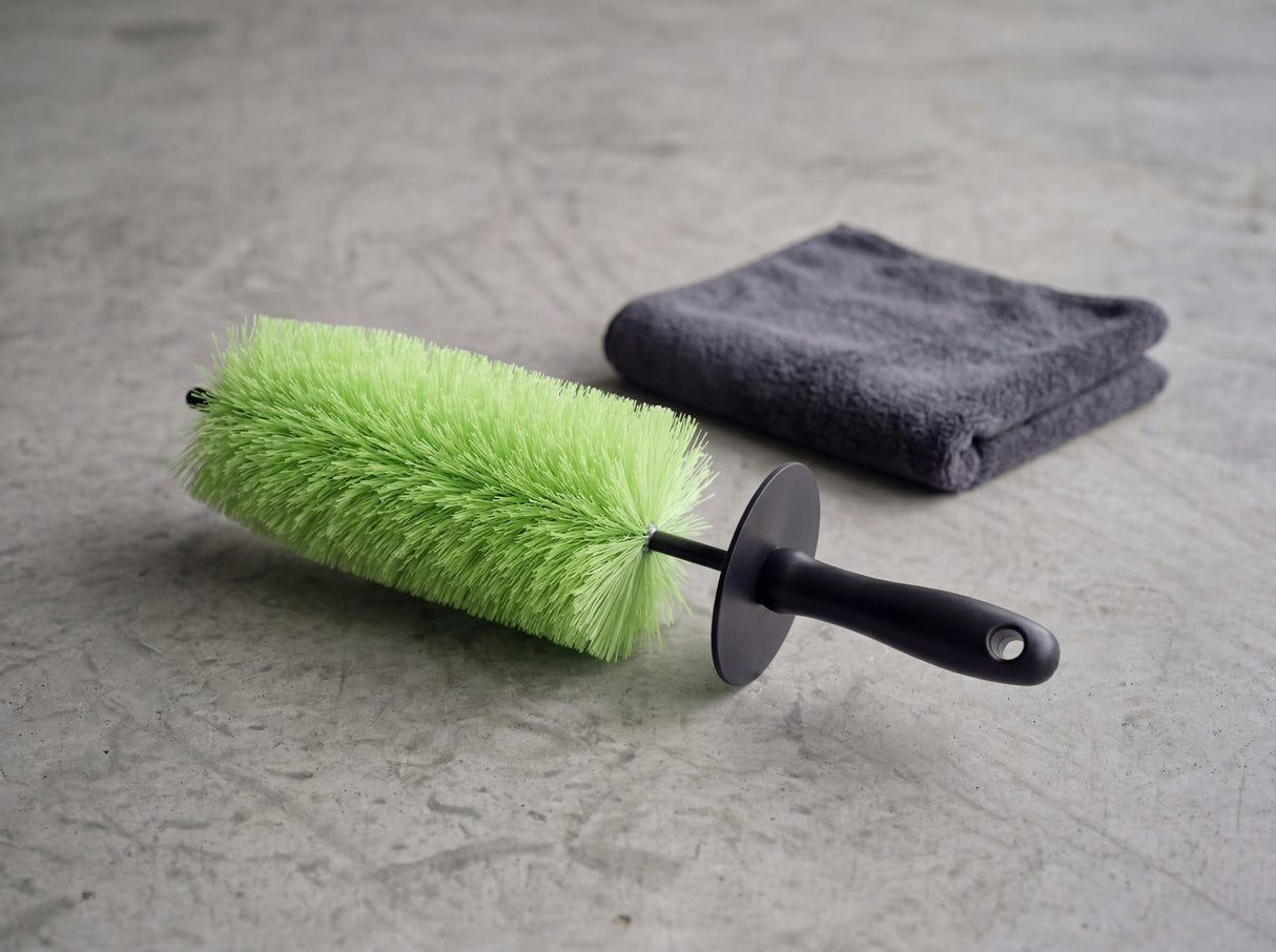 TUGA Chemie Felgenbürste horizontal auf Betonvorplatz neben grauem Mikrofasertuch