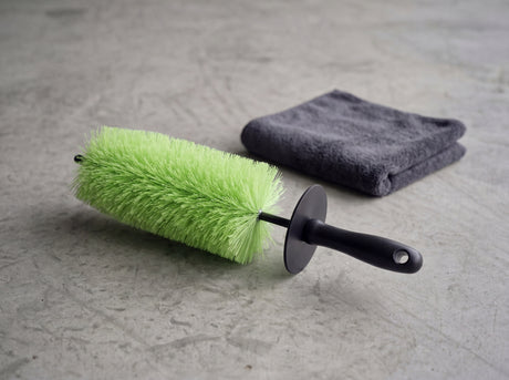 TUGA Chemie Felgenbürste horizontal auf Betonvorplatz neben grauem Mikrofasertuch